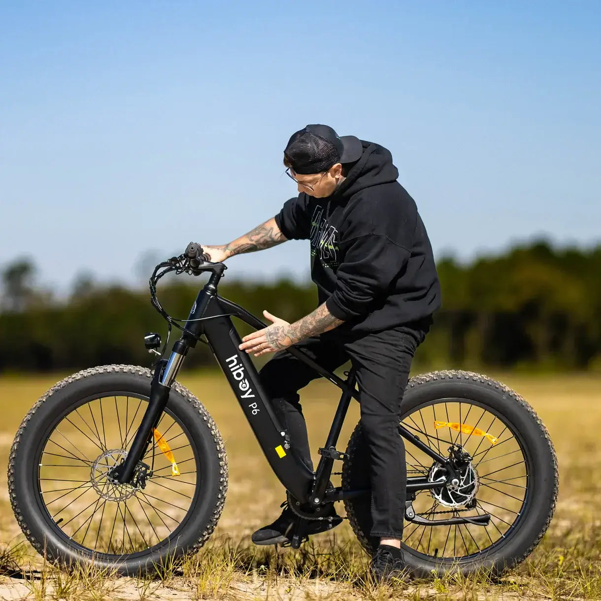 Person riding a Hiboy P6 fat tire electric bike in an outdoor setting, showcasing its design and versatility.