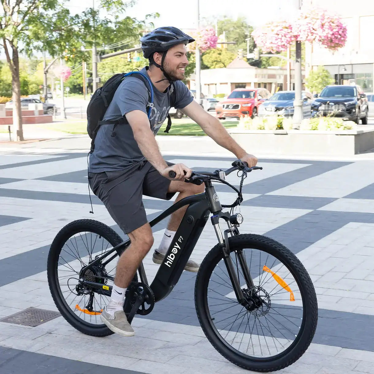 Man riding the Hiboy P7 E-Bike through a city pathway, showcasing its stylish design and urban commuting capabilities.