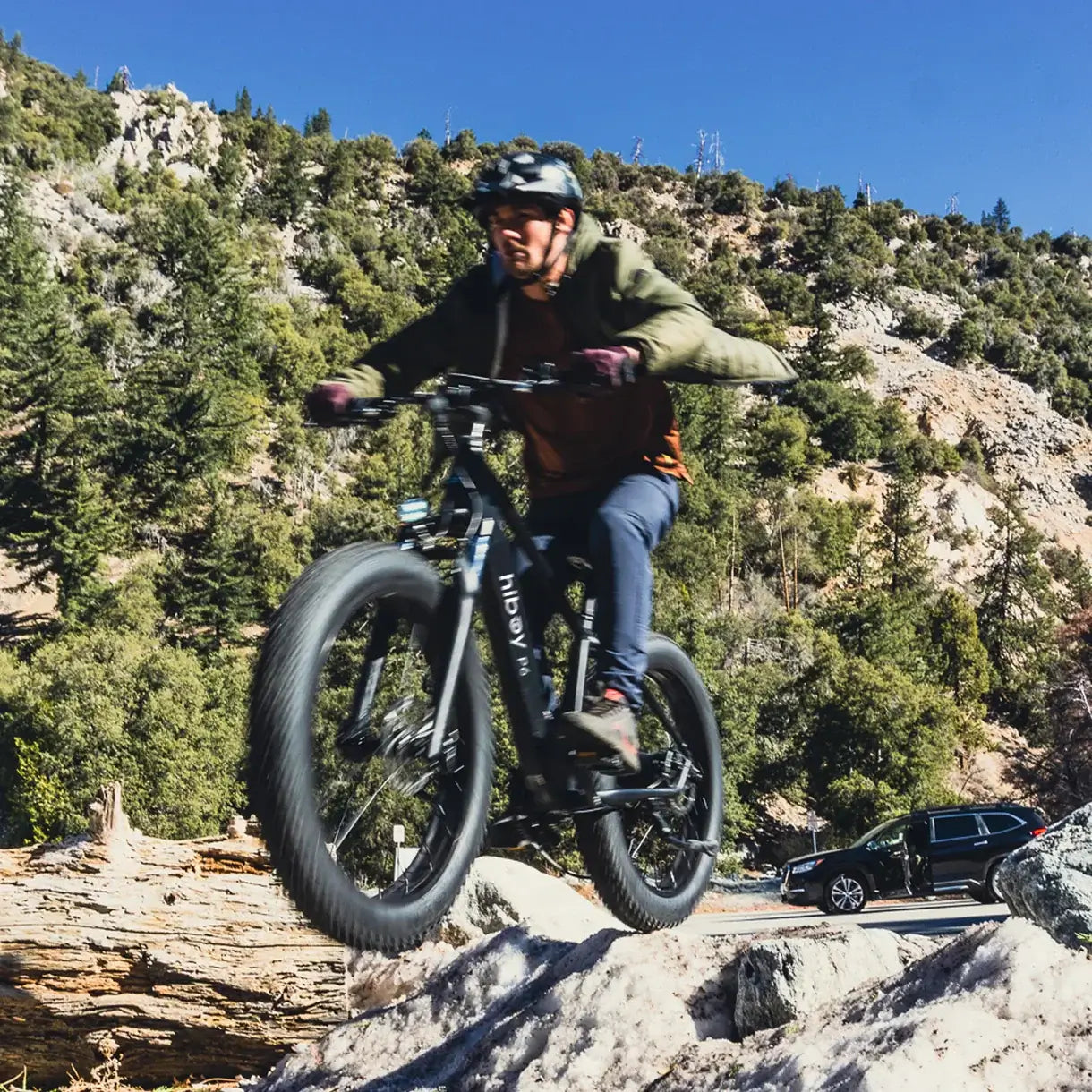 Person riding a Hiboy P6 fat tire e-bike over the rocky terrain, showcasing its off-road capabilities.