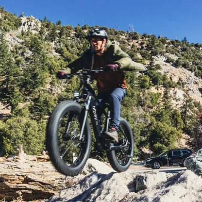 Person riding a Hiboy P6 fat tire e-bike over the rocky terrain, showcasing its off-road capabilities.