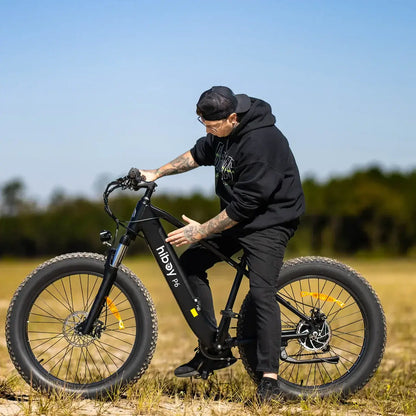 Person riding a Hiboy P6 fat tire electric bike in an outdoor setting, showcasing its design and versatility.